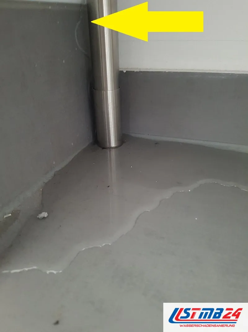 24-Stunden-Notdienst: Wasserlache breitet sich vom Edelstahlrohr über den Kellerboden aus, ein gelber Pfeil zeigt auf das Rohr
