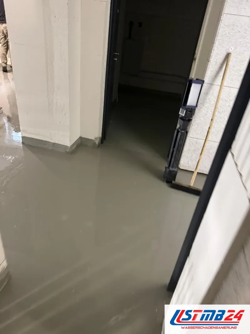 24-Stunden-Notdienst: Kellergang unter Wasser, an der Wand ein Baustrahler auf dem Stativ und ein Wasserschieber