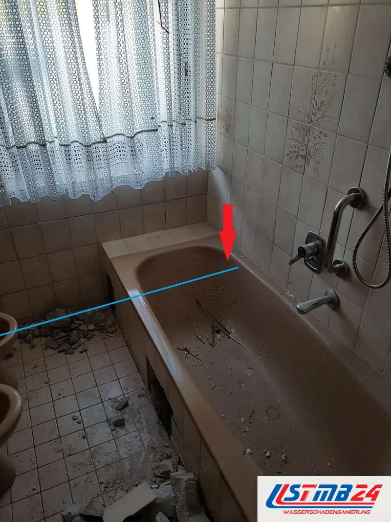 Badsanierung vorher: braunbeige Wanne mit Dekorfliesen, Schutt in der Wanne, Linie und Pfeil markieren die Wannenecke