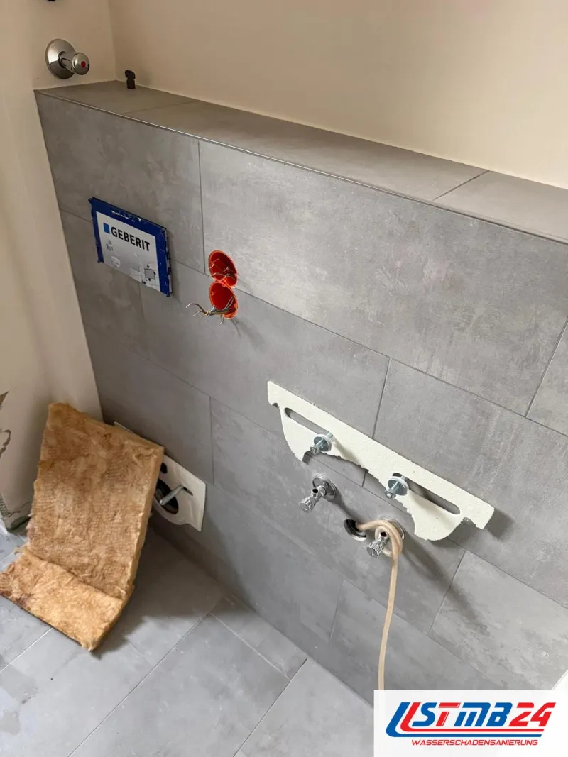 Badsanierung: geflieste Vorwand mit Schutzkarton der Betätigungsplatte, roter Elektrodose, WC-Bolzen und Eckventilen