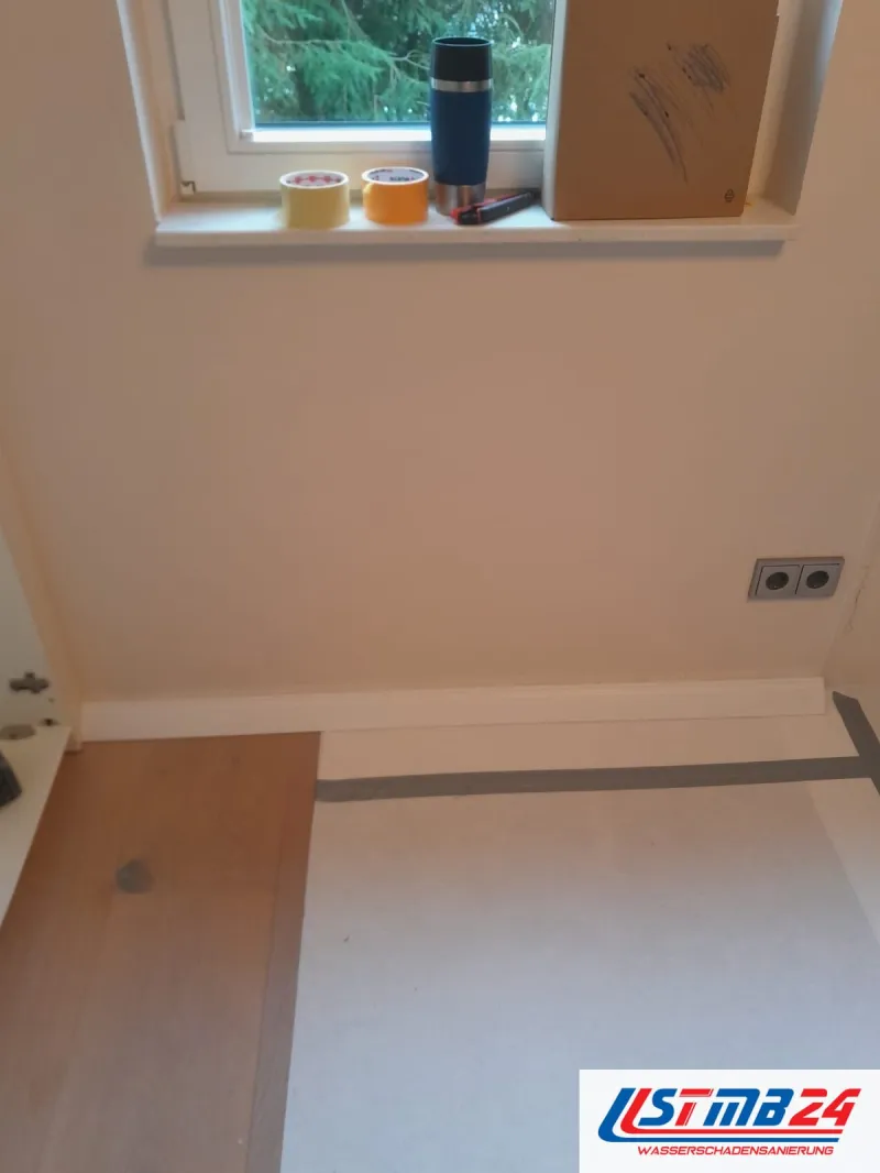 Bodenbelagsarbeiten: Holzdielen in einem Zimmer teils mit Vlies abgedeckt, auf der Fensterbank Klebebänder