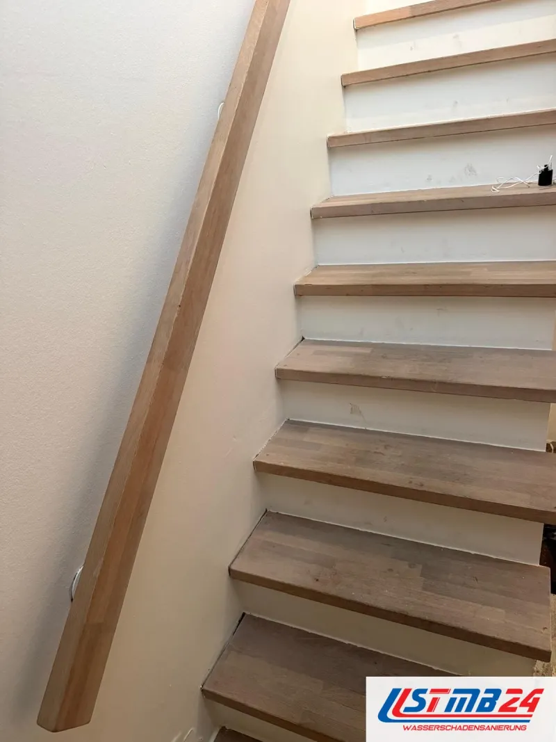 Bodenbelagsarbeiten an der Treppe: Holzstufen mit abgetretenen Kanten, an der Wand ein Handlauf aus Holz