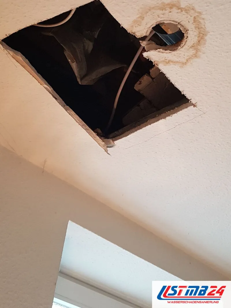 Quadratisch geöffnete Decke, daneben ein Deckenauslass mit braunem Rand, aus dem ein Kabel hängt
