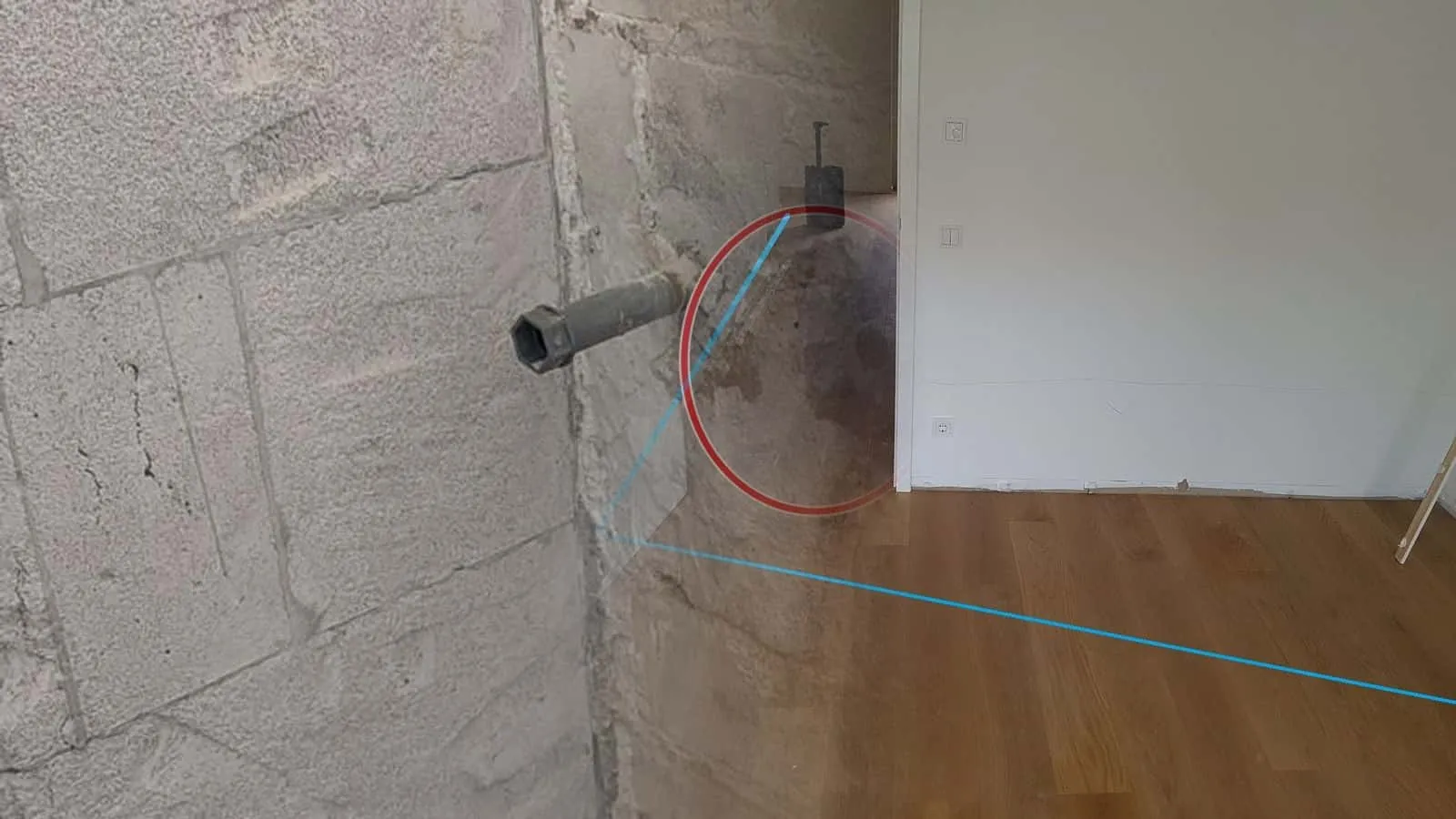 Parkett mit blauer Linie von der Tür zur Wand, dahinter im Flur ein laufendes Trocknungsgerät