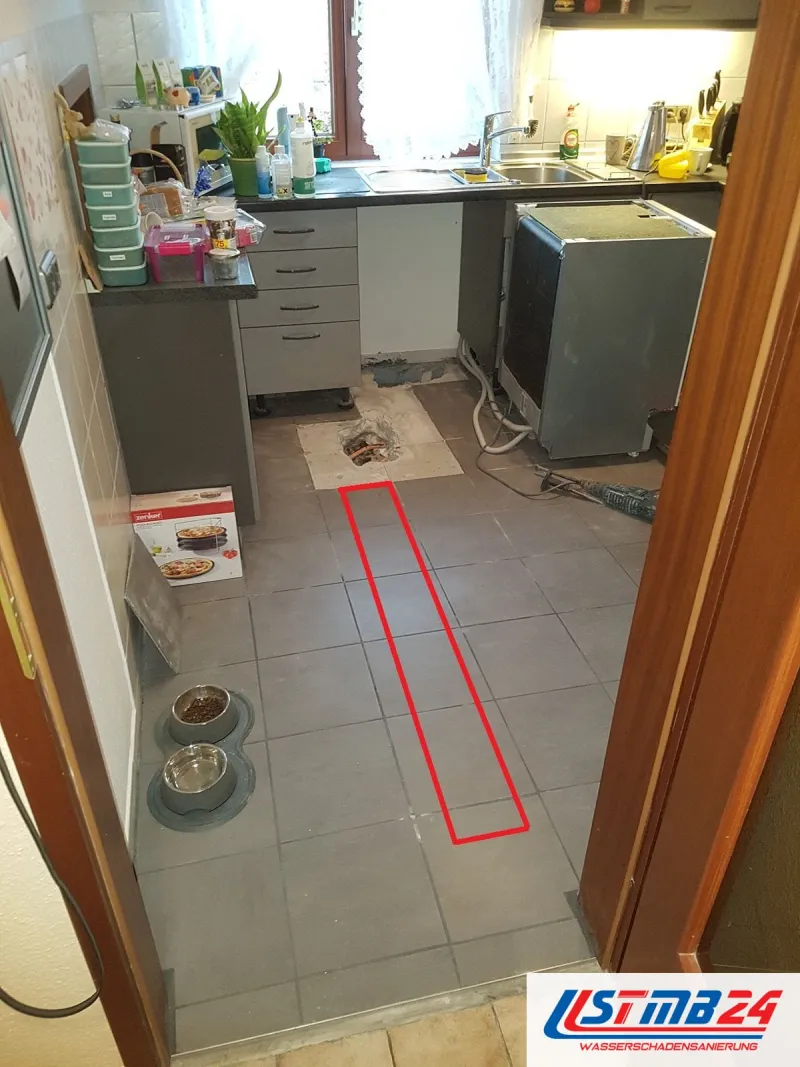 Küche mit grauen Bodenfliesen, vor der Spüle eine kleine Öffnung im Boden, ein rotes Rechteck zeichnet den Weg der Leitung zur Tür nach