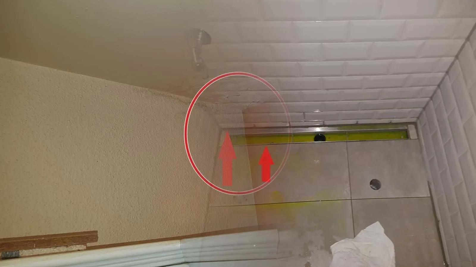 Bodengleiche Dusche mit gelbem Färbemittel in der Duschrinne und roten Pfeilen auf die Ränder