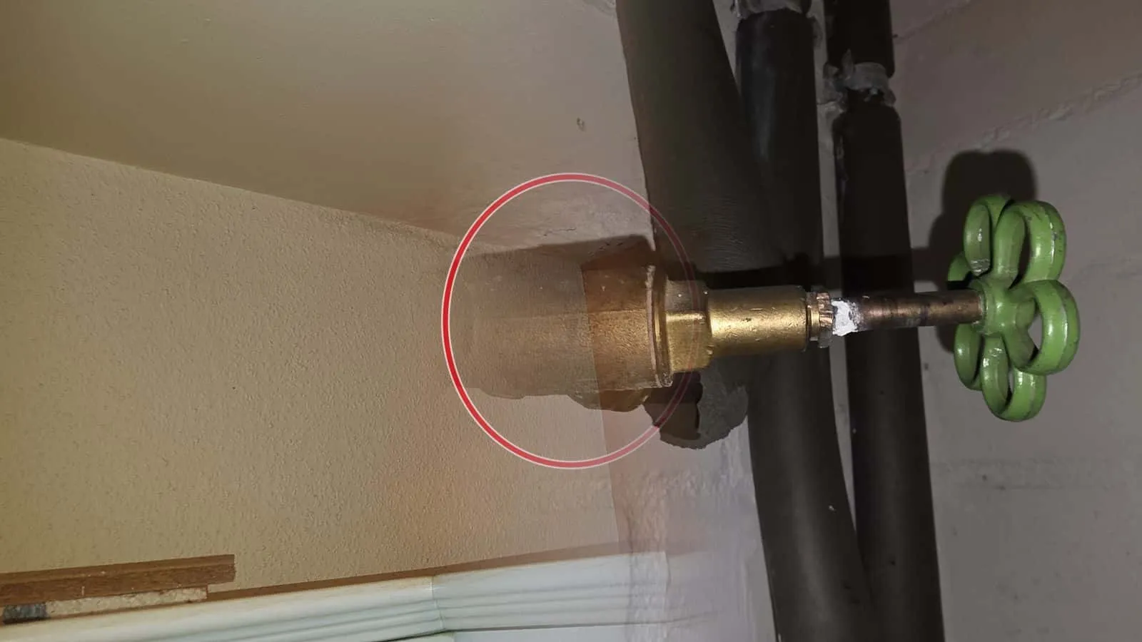 Absperrventil mit grünem Handrad an einer Kellerwand