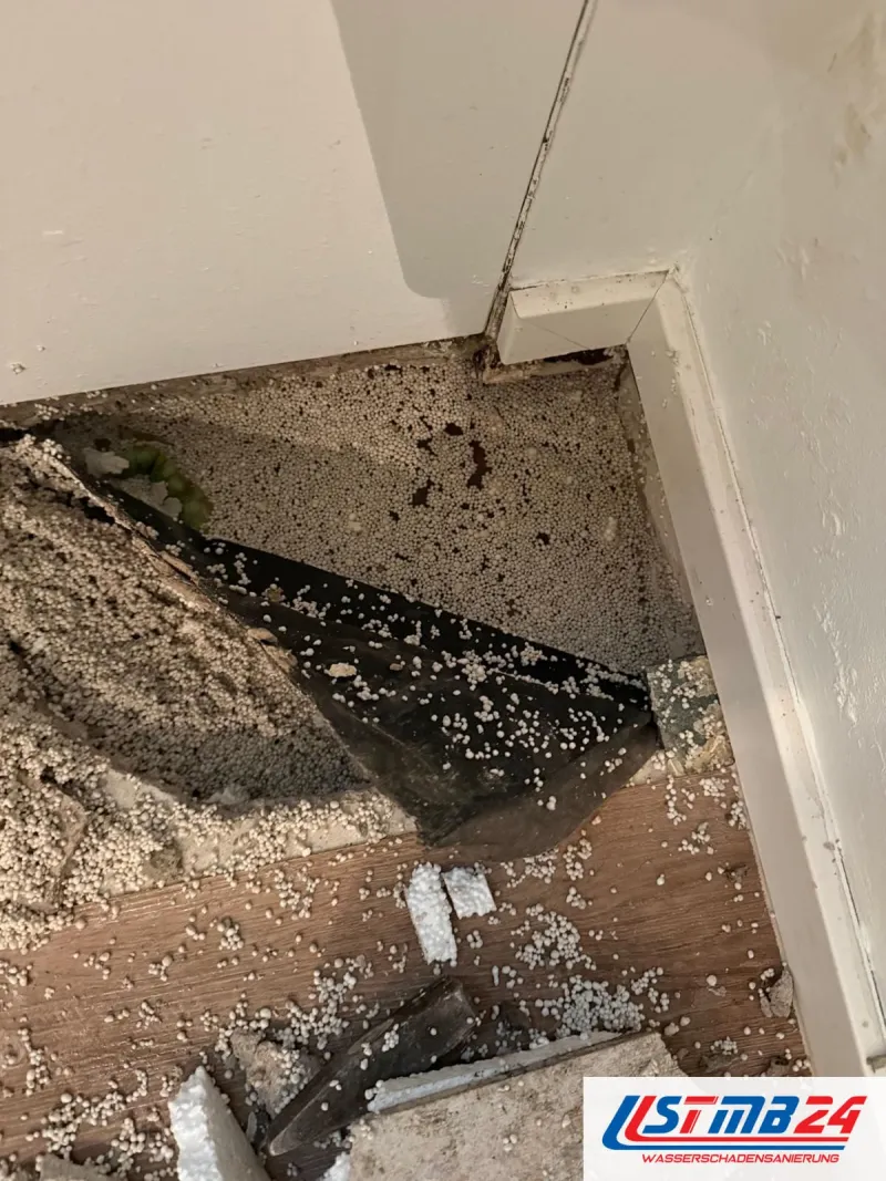 Aufgenommener Fußboden in der Raumecke, unter der schwarzen Bahn liegt eine feuchte Schüttung aus hellen Kügelchen