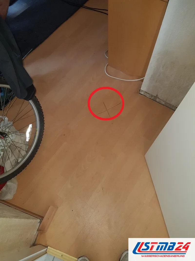 Laminat in Buchenoptik, ein roter Kreis um ein mit Bleistift markiertes Kreuz auf dem Boden
