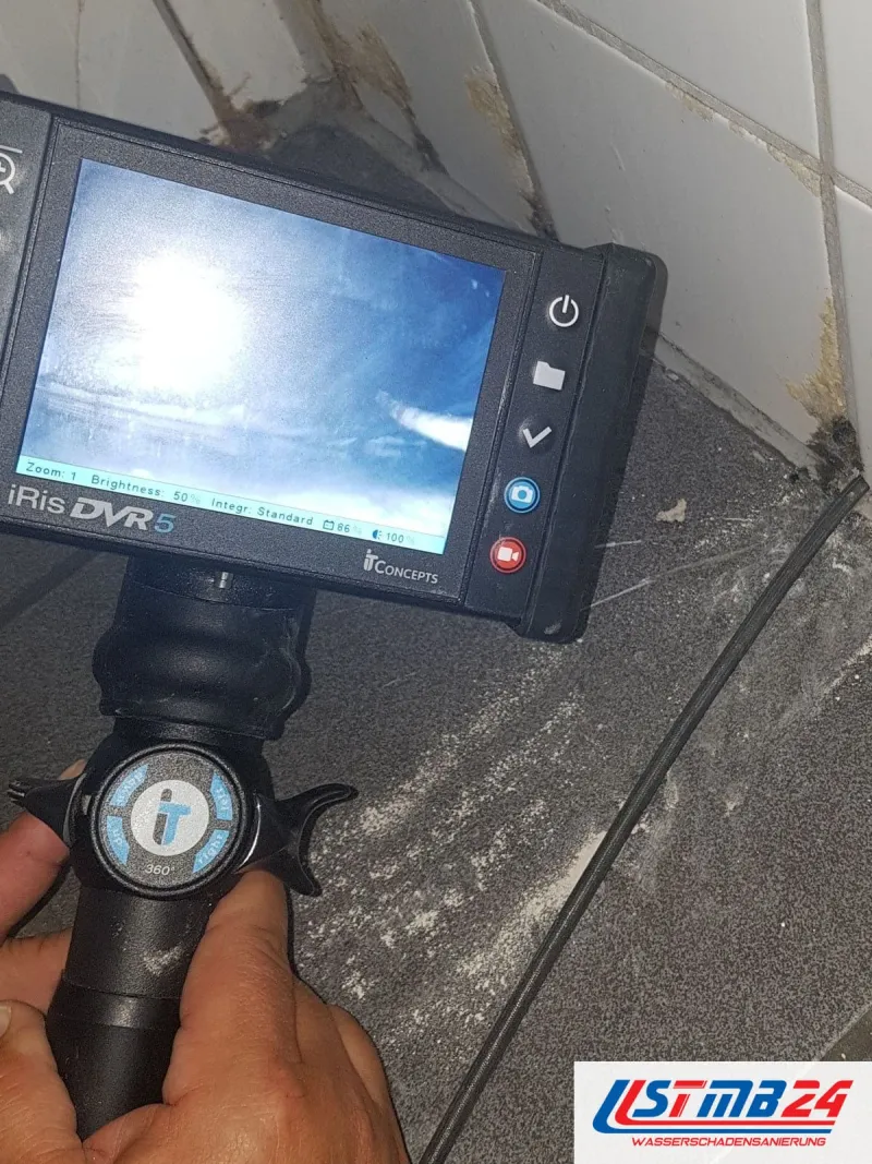 Endoskop mit eingeschaltetem Monitor über hellen Fliesen, die Sonde führt zur Fuge einer Duschtasse