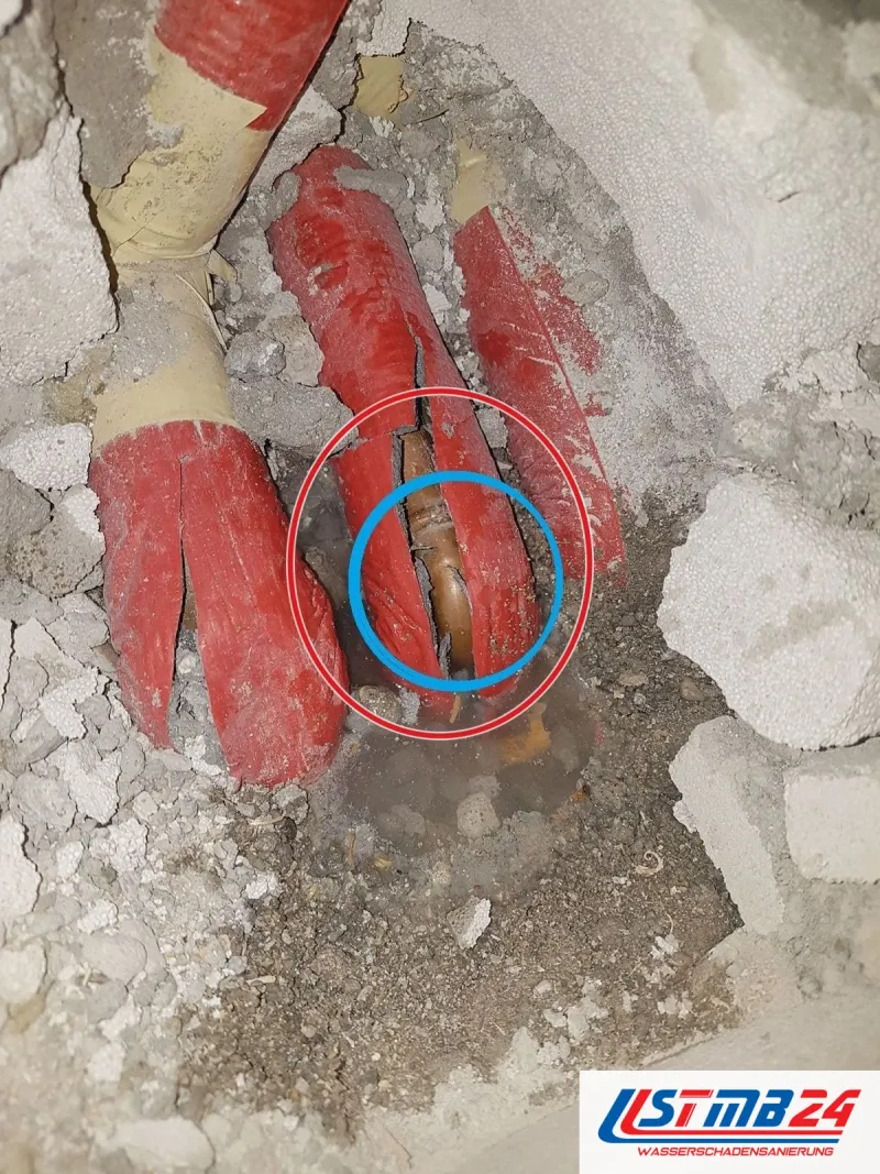 rote Rohrdämmung im aufgestemmten Estrich, blau umkreist die Leckstelle, ein roter Kreis markiert die Stelle