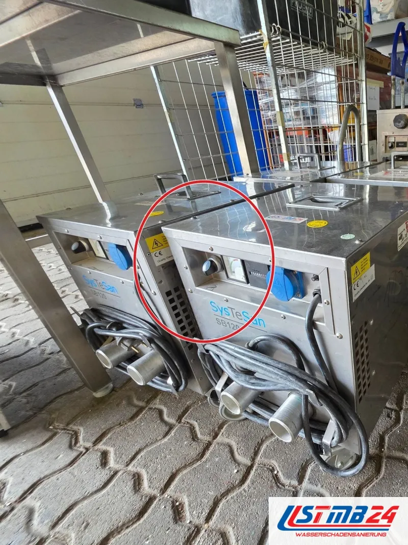 Edelstahlgeräte SysTeSan SB120 mit aufgewickelten Kabeln und Schlauchanschlüssen im Hof, ein roter Kreis markiert die Stelle
