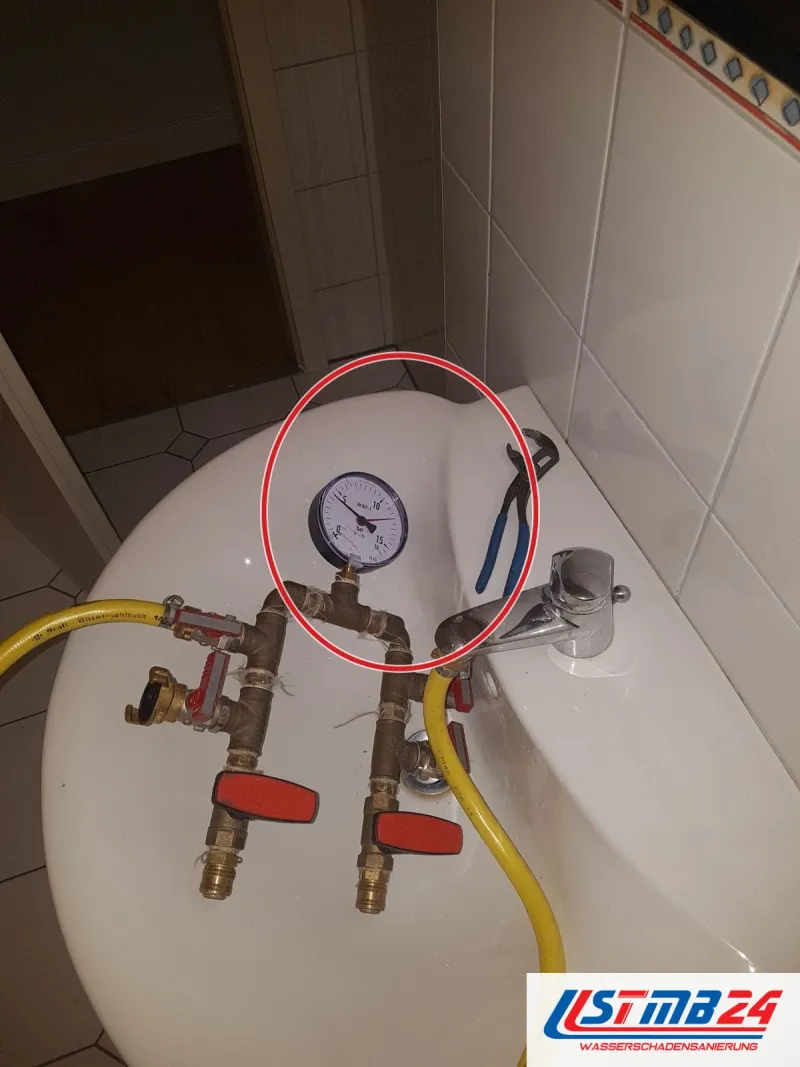 Druckprüfgerät mit Manometer auf einer weißen Fläche, ein roter Kreis markiert die Stelle