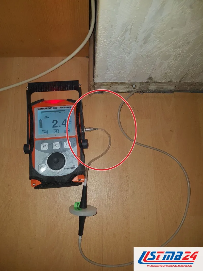 Messgerät mit Anzeige auf dem Laminat, Kabel zur Wand, ein roter Kreis markiert die Stelle