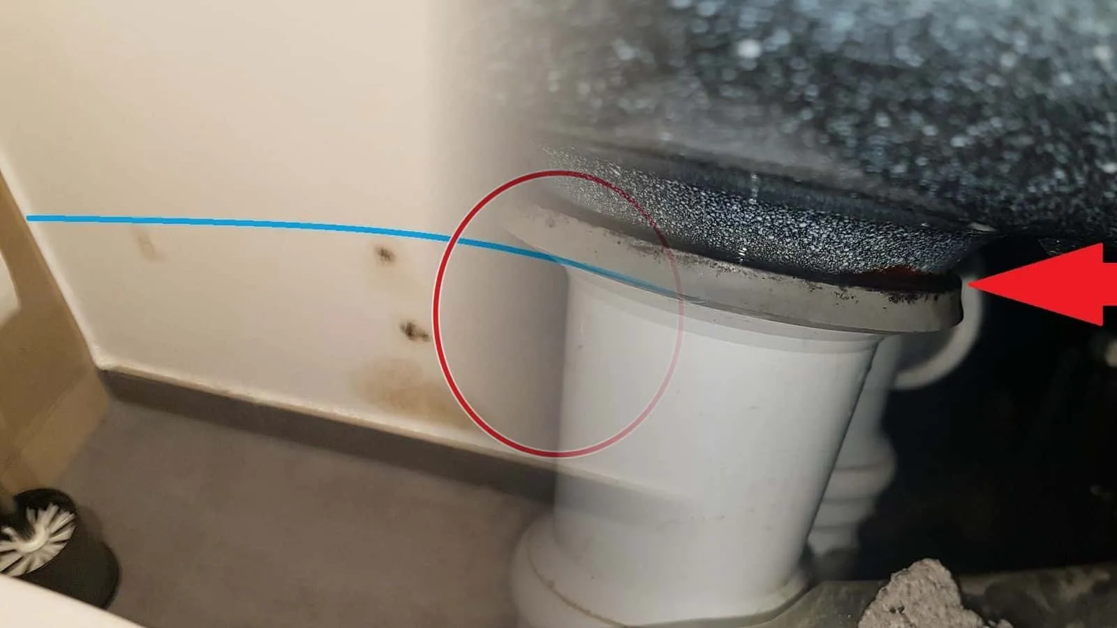 Ablauf unter einer Duschtasse, ein roter Pfeil zeigt auf die undichte Dichtung