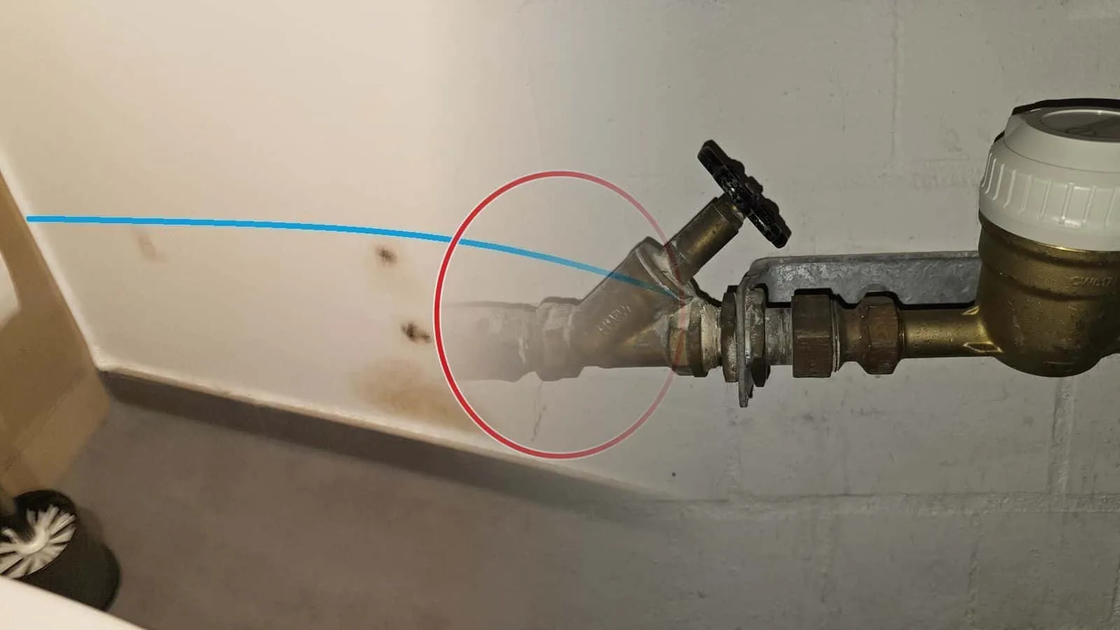 Messingventil mit Entleerung vor dem Wasserzähler an einer weiß gestrichenen Kellerwand