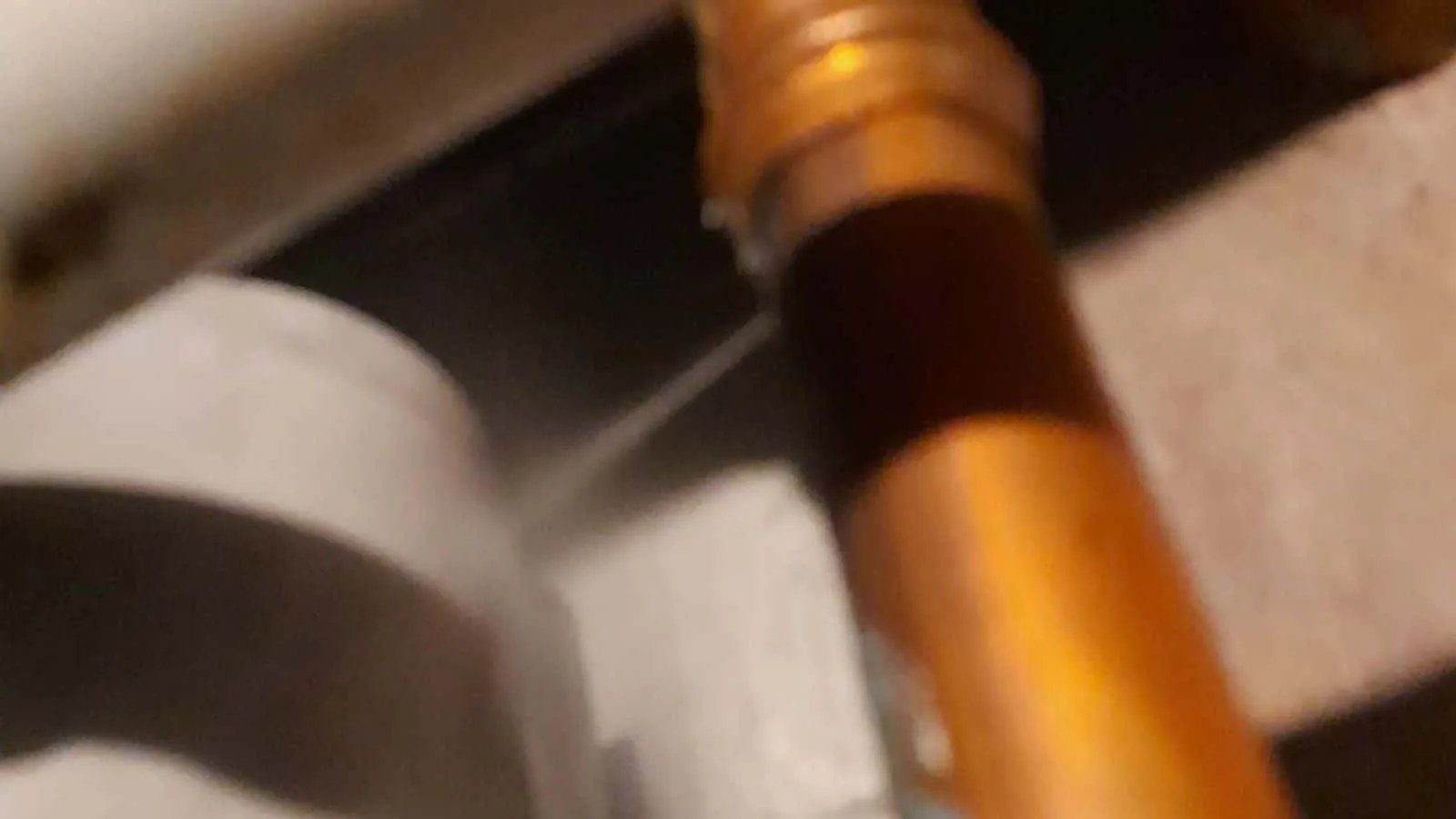 Kupferrohr am Pressfitting, aus dem ein feiner Wasserstrahl spritzt
