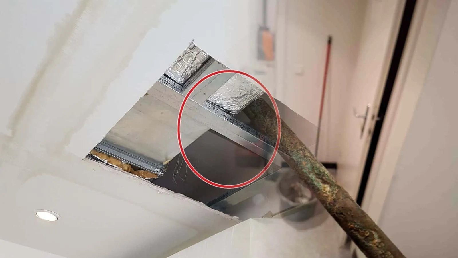 Ausgebautes altes Rohrstück mit grünlich braunem Korrosionsbelag, im Hintergrund ein Kellerflur mit Steinboden und Eimer