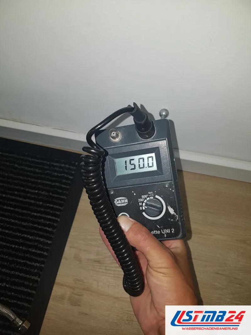 Messgerät mit Anzeige 150,0 in der Hand vor einem Heizkörper
