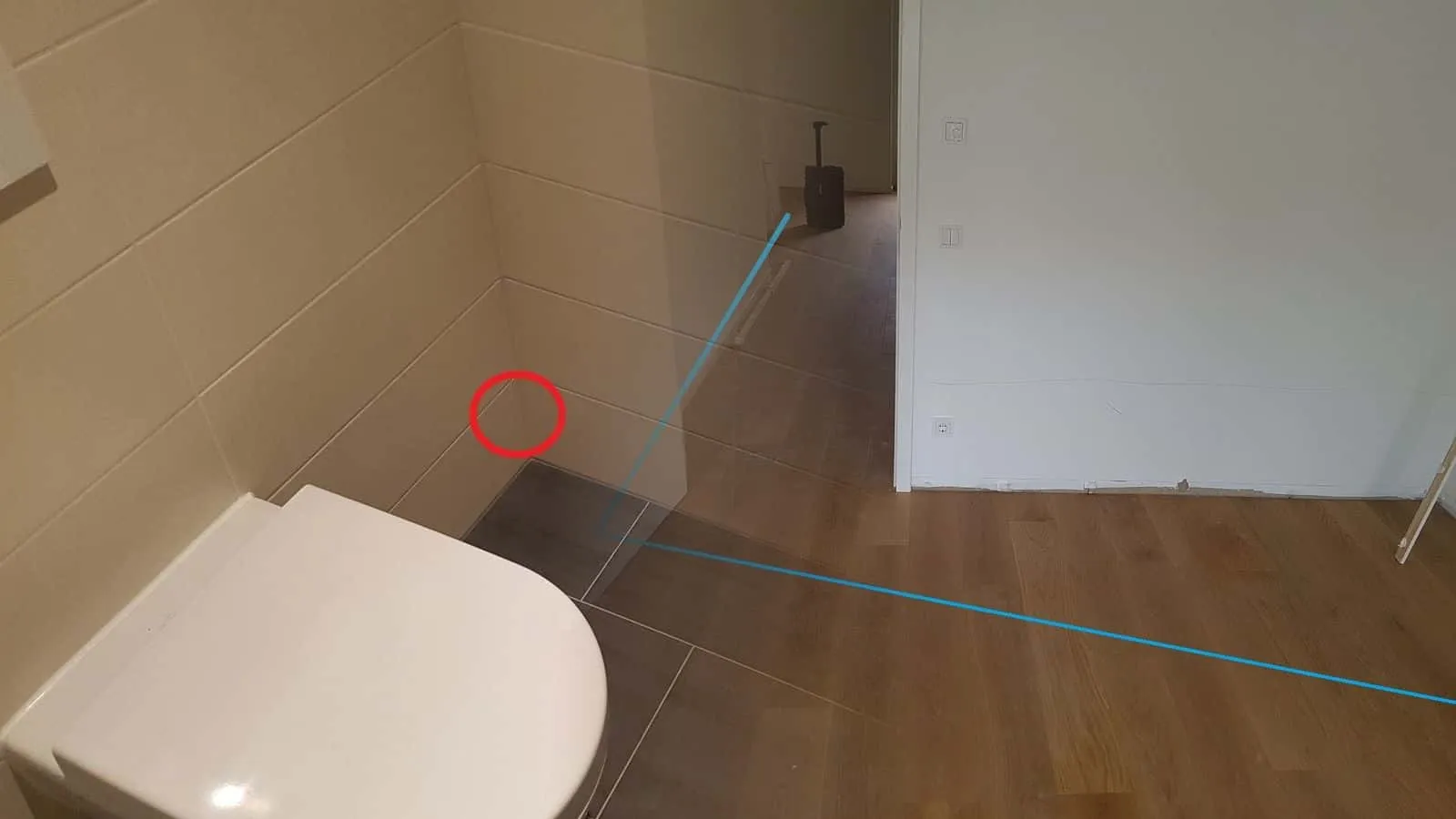 Wohnraum mit blauer Linie auf dem Parkett von der Tür bis zur Wand, im Flur dahinter läuft ein Trocknungsgerät