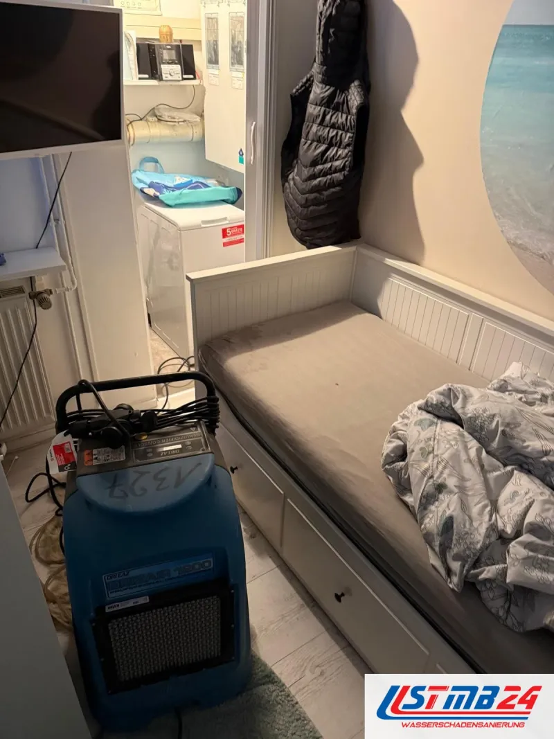 Blauer Bautrockner in einer Ferienwohnung zwischen Bettsofa und Küchenzeile, das Kabel liegt auf dem Fliesenboden