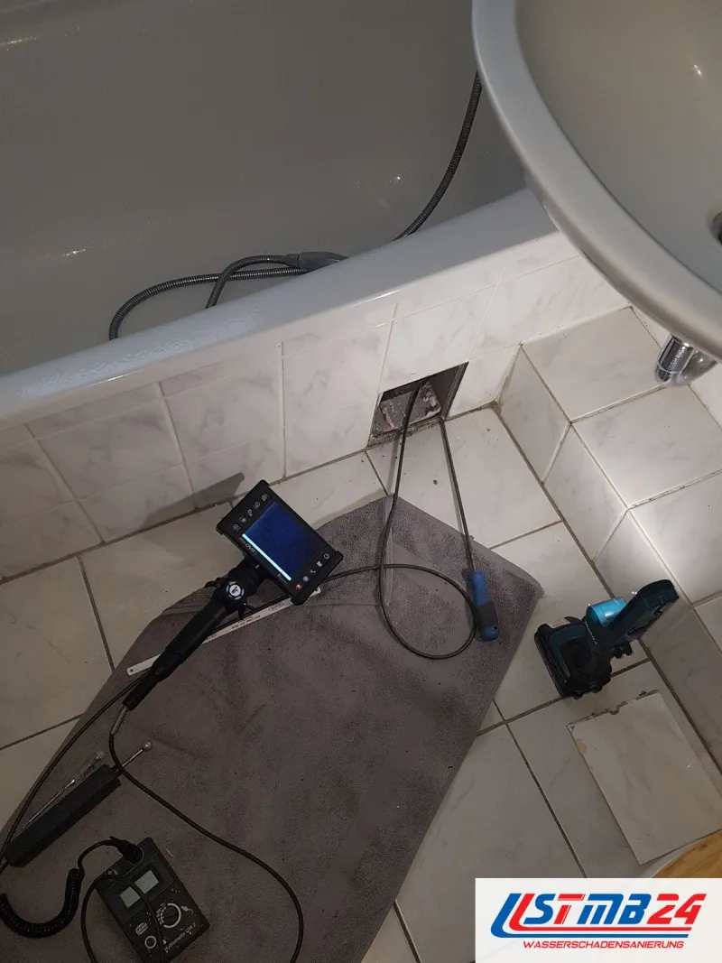 Endoskop und Ortungsgerät auf der Badematte, die Sonde führt in die Revisionsöffnung an der Wannenverkleidung