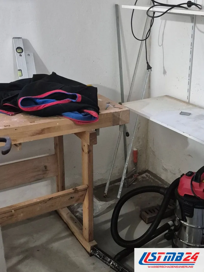 Hobbykeller mit Werkbank und Wandregal, am Boden ein Nasssauger mit Schlauch
