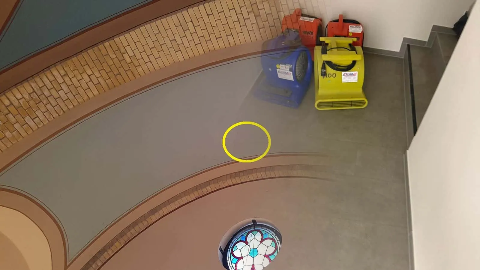 Vier Gebläse in Rot, Blau und Gelb am Fuß einer Treppe