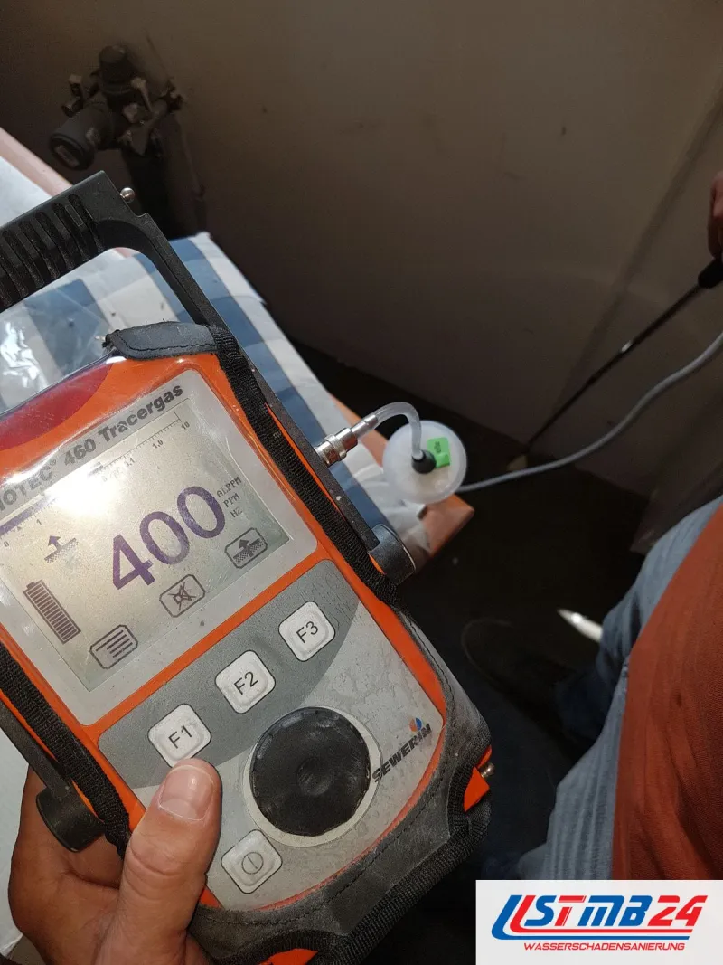 Tracergas-Messgerät in der Hand zeigt 400 ppm Wasserstoff, am Schlauch hängt die Saugglocke, dahinter Fensterbank und Wand