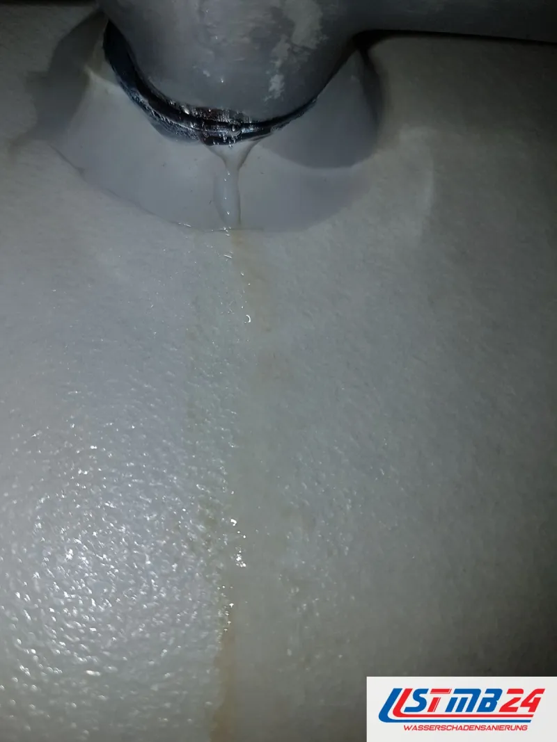 Graues Ablaufrohr unter einer Wanne, vom Anschluss läuft eine gelbliche Wasserspur über den weißen Wannenträger