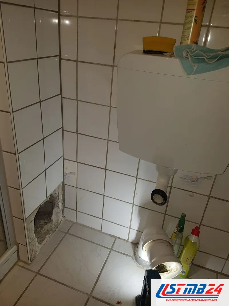 Kleine Öffnung in der Fliesenwand neben dem WC, eine Lampe auf dem Boden leuchtet hinein