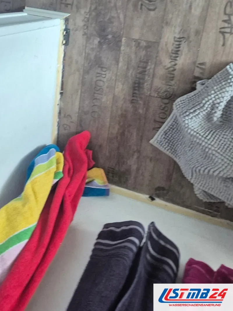 Bunte Handtücher ausgebreitet auf einem Boden mit Weinkistenmuster vor einer weißen Badewanne
