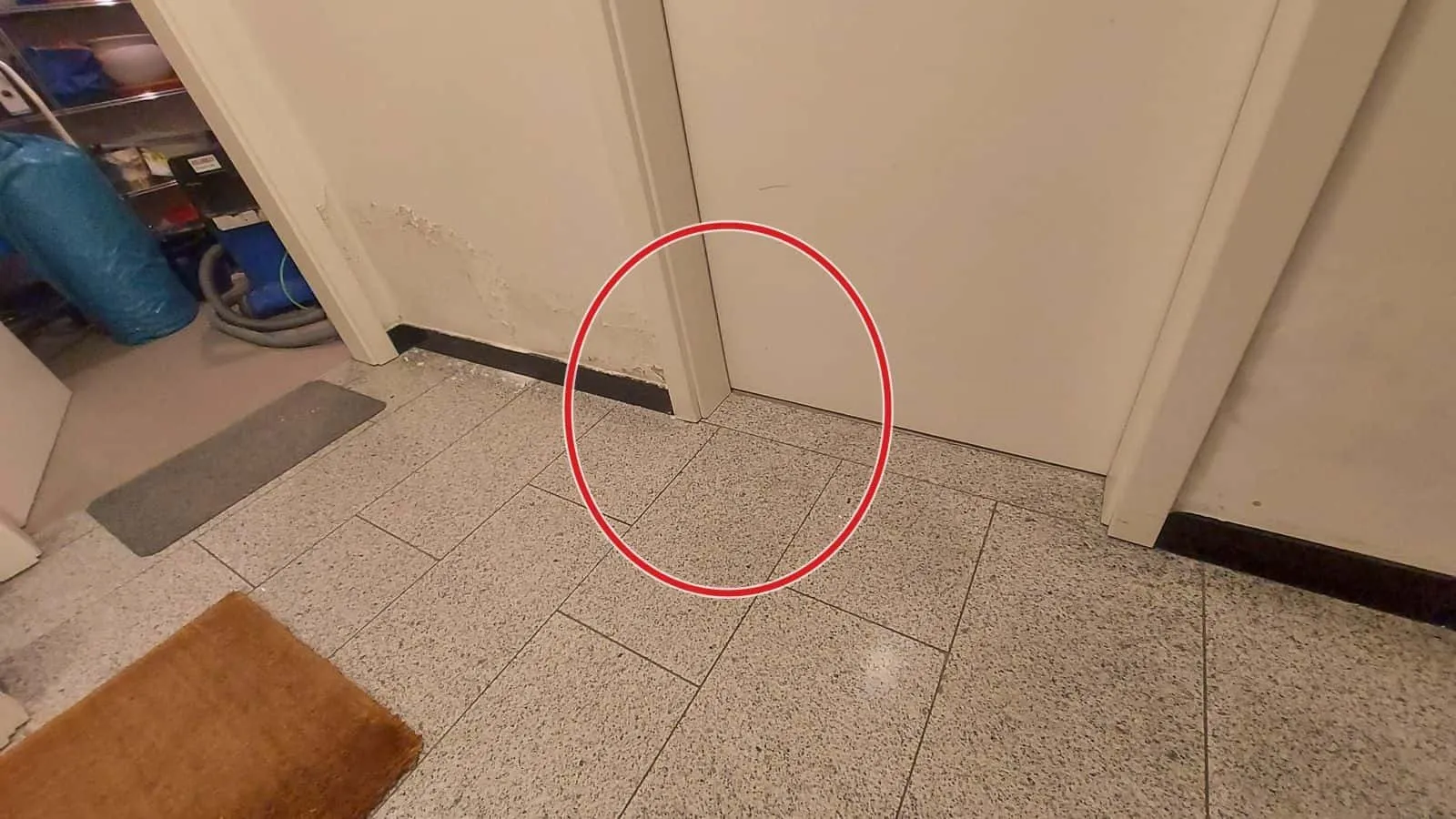 Flur mit Steinboden und dunklen Feuchteflecken unten an der Wand