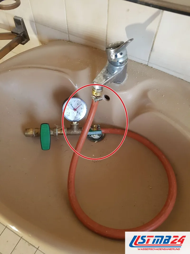 Waschbecken mit Prüfventil und rotem Schlauch, ein roter Kreis markiert die Stelle