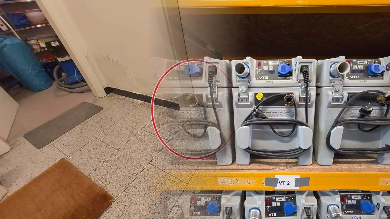 Drei graue Trocknungsmodule mit Steckdose und aufgewickeltem Kabel in einem Regalfach