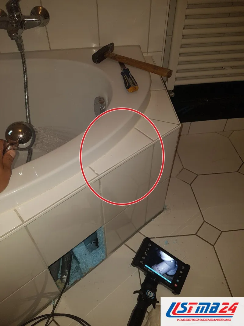 Eckbadewanne mit Hammer, Endoskop davor, ein roter Kreis markiert die Stelle