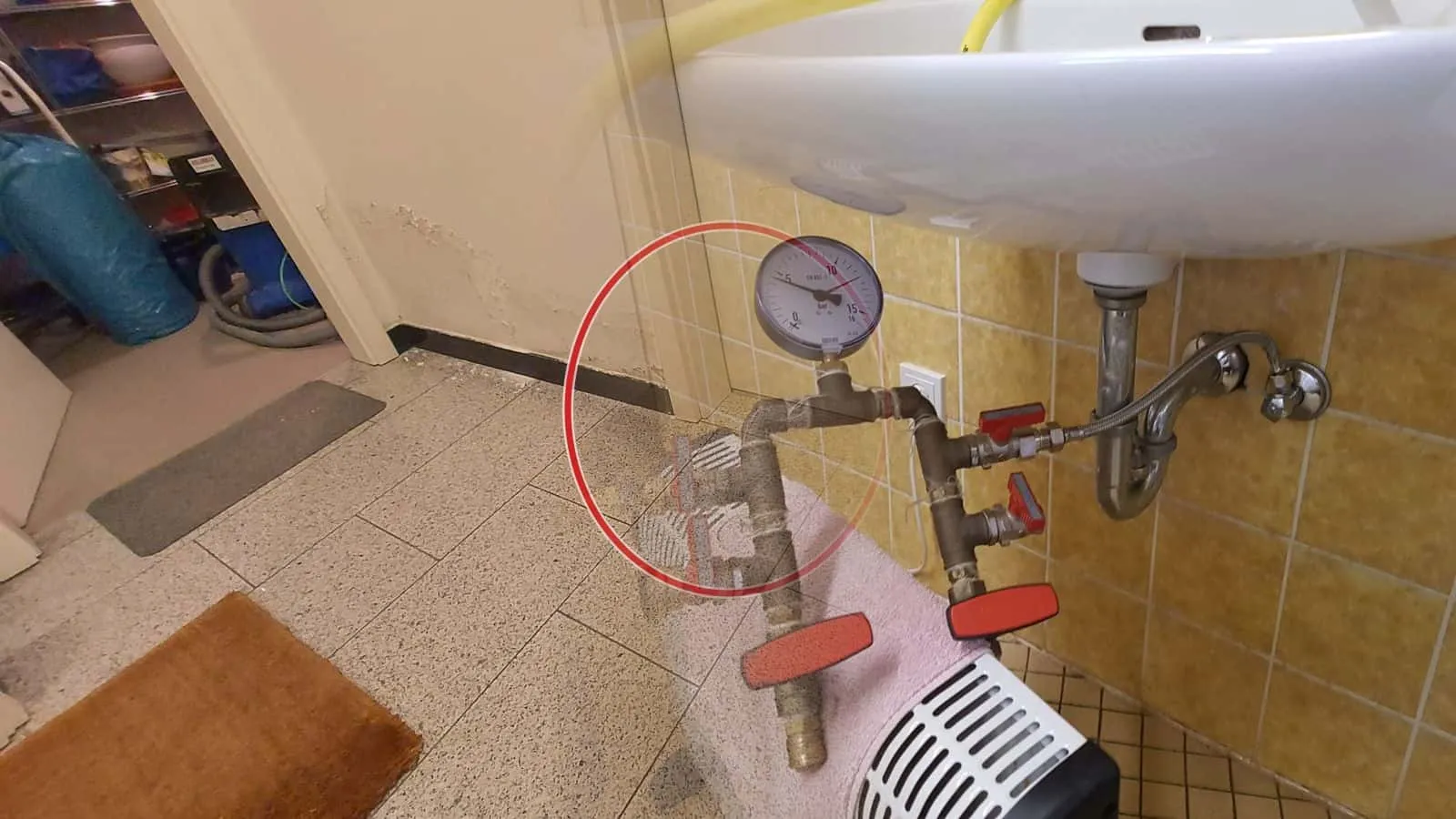 Prüfventile mit Manometer unter einem Waschbecken vor gelben Fliesen
