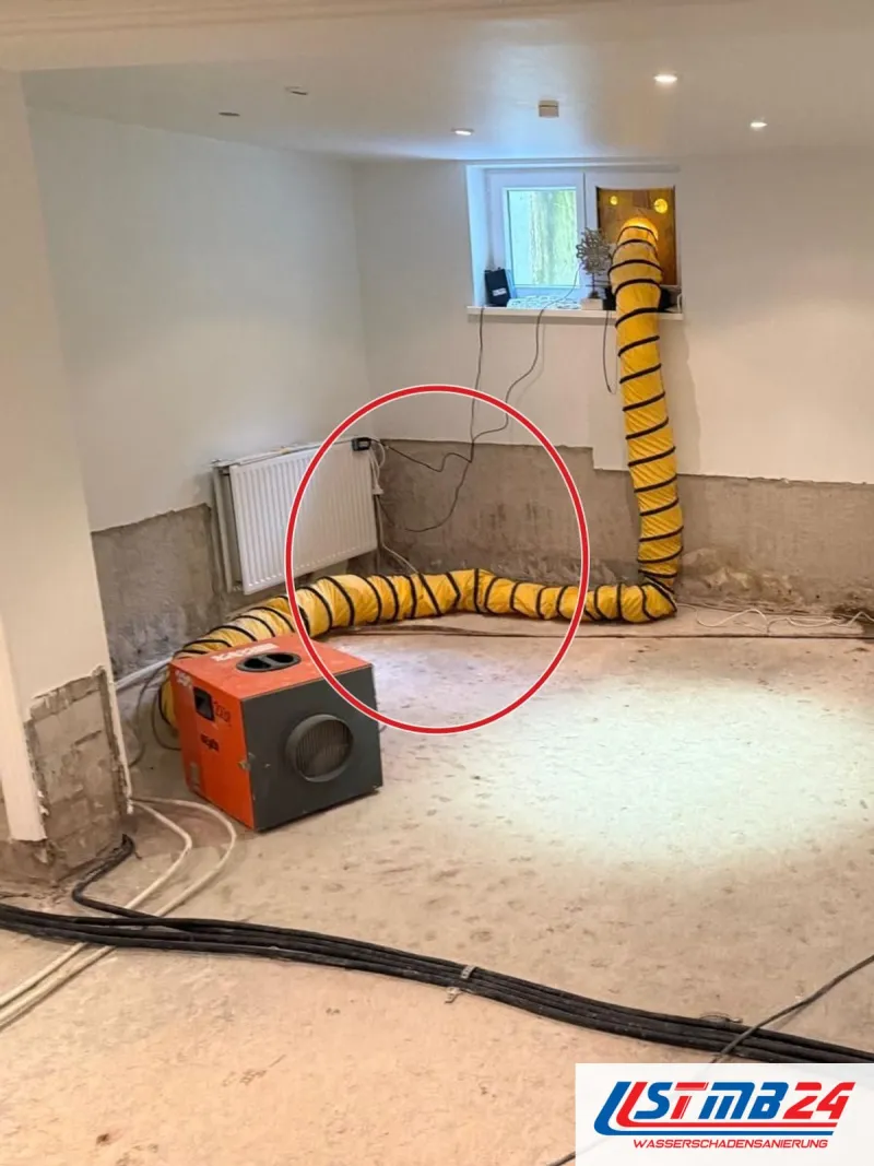 Putz bis Kniehöhe abgeschlagen, orangefarbenes Gerät mit gelbem Luftschlauch zum Kellerfenster, ein roter Kreis markiert die Stelle