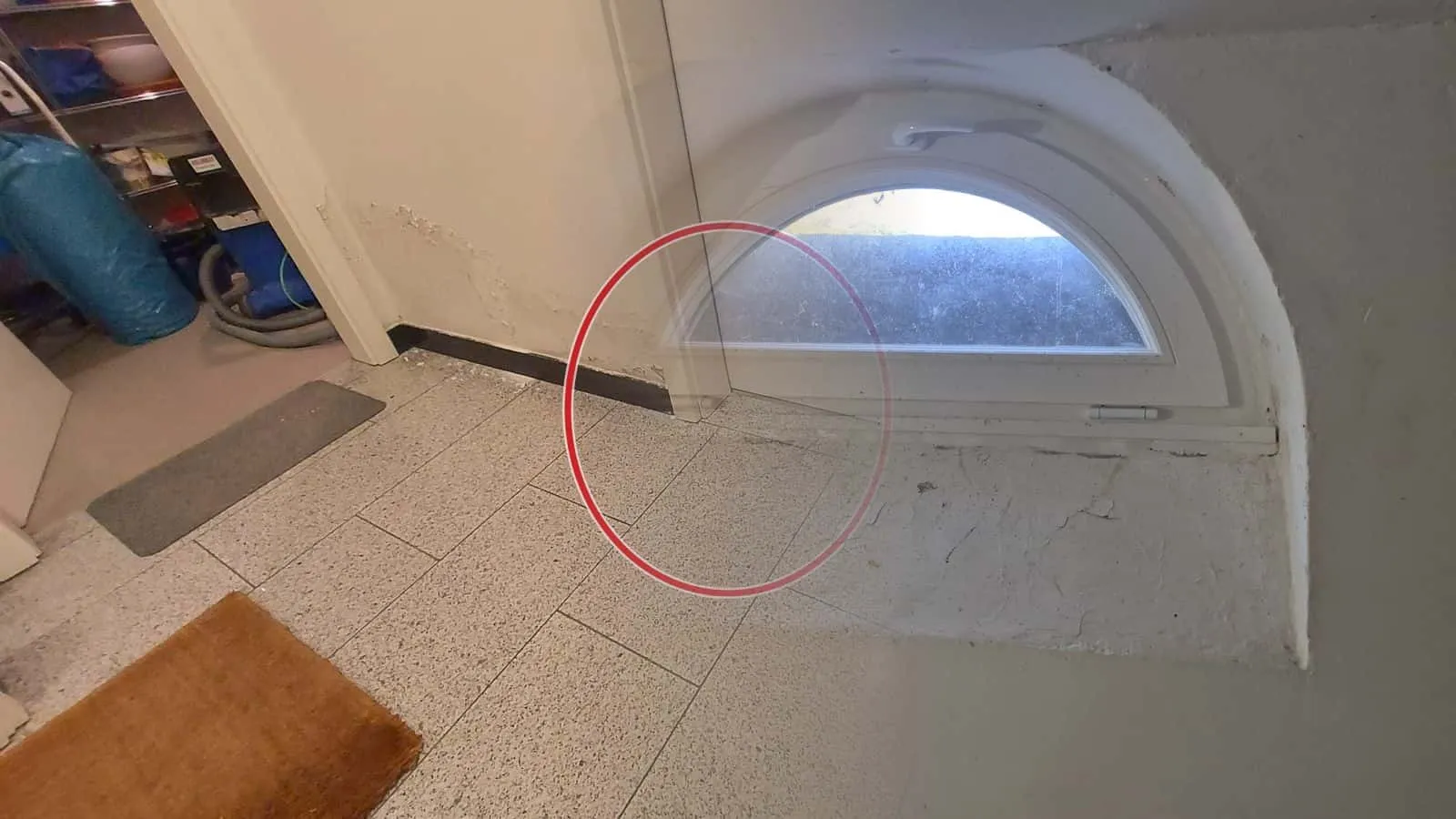 Halbrundfenster mit Kippflügel in tiefer Laibung, darunter abgeplatzte Farbe auf dem Putz