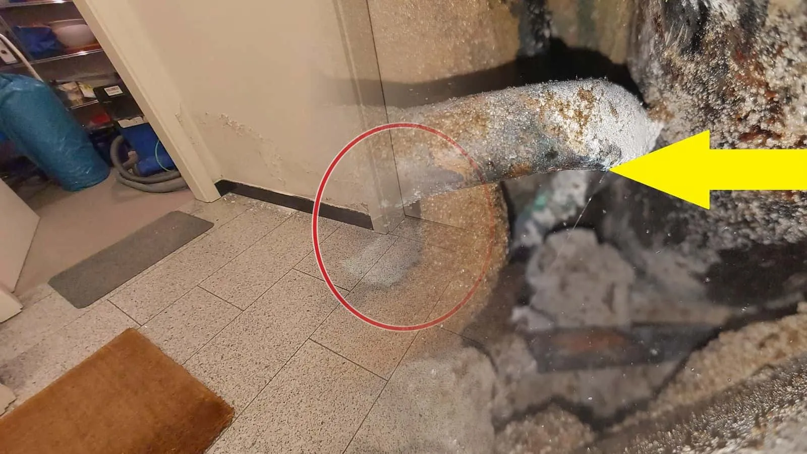 Korrodiertes Kupferrohr mit Kalkablagerung, ein gelber Pfeil zeigt auf die Stelle