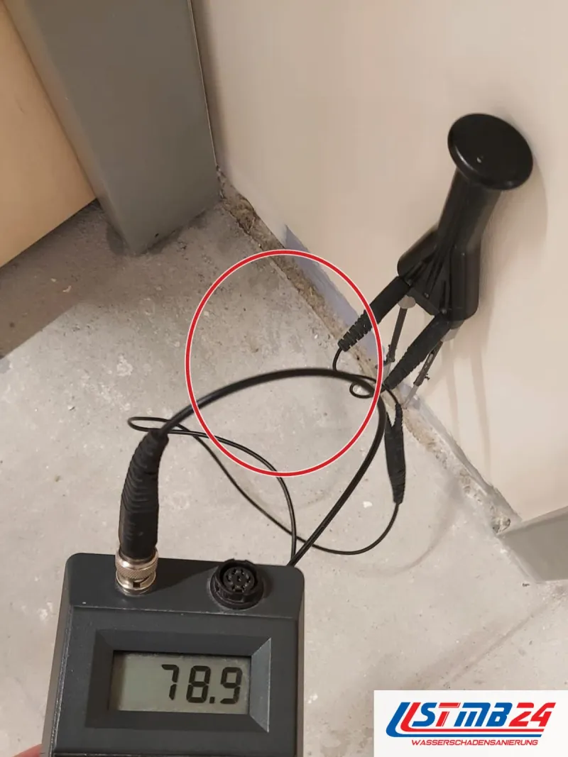 Messgerät zeigt 78,9, zwei Elektroden an einer Wandecke über unbelegtem Estrich, die Hand an der Messtaste, ein roter Kreis markiert die Stelle