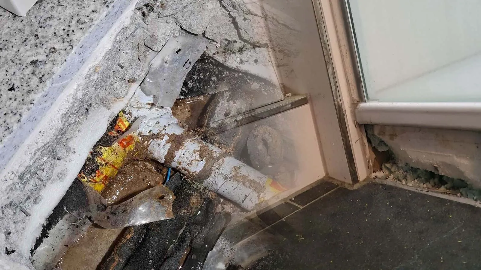 lose Fliesenplatte auf der Fensterbank, dahinter grüne Dämmung mit Schimmelspuren