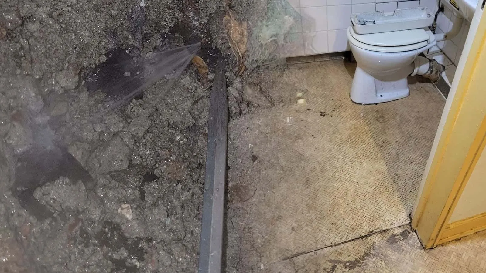 Pfützen vor dem WC auf einem Kunststoffboden im Flechtmuster