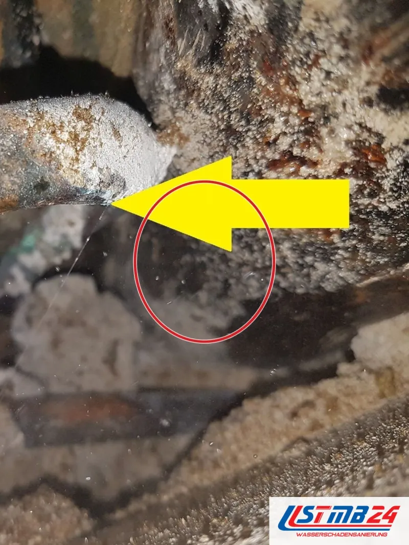 korrodiertes Kupferrohr mit Kalkablagerung, gelber Pfeil, ein roter Kreis markiert die Stelle