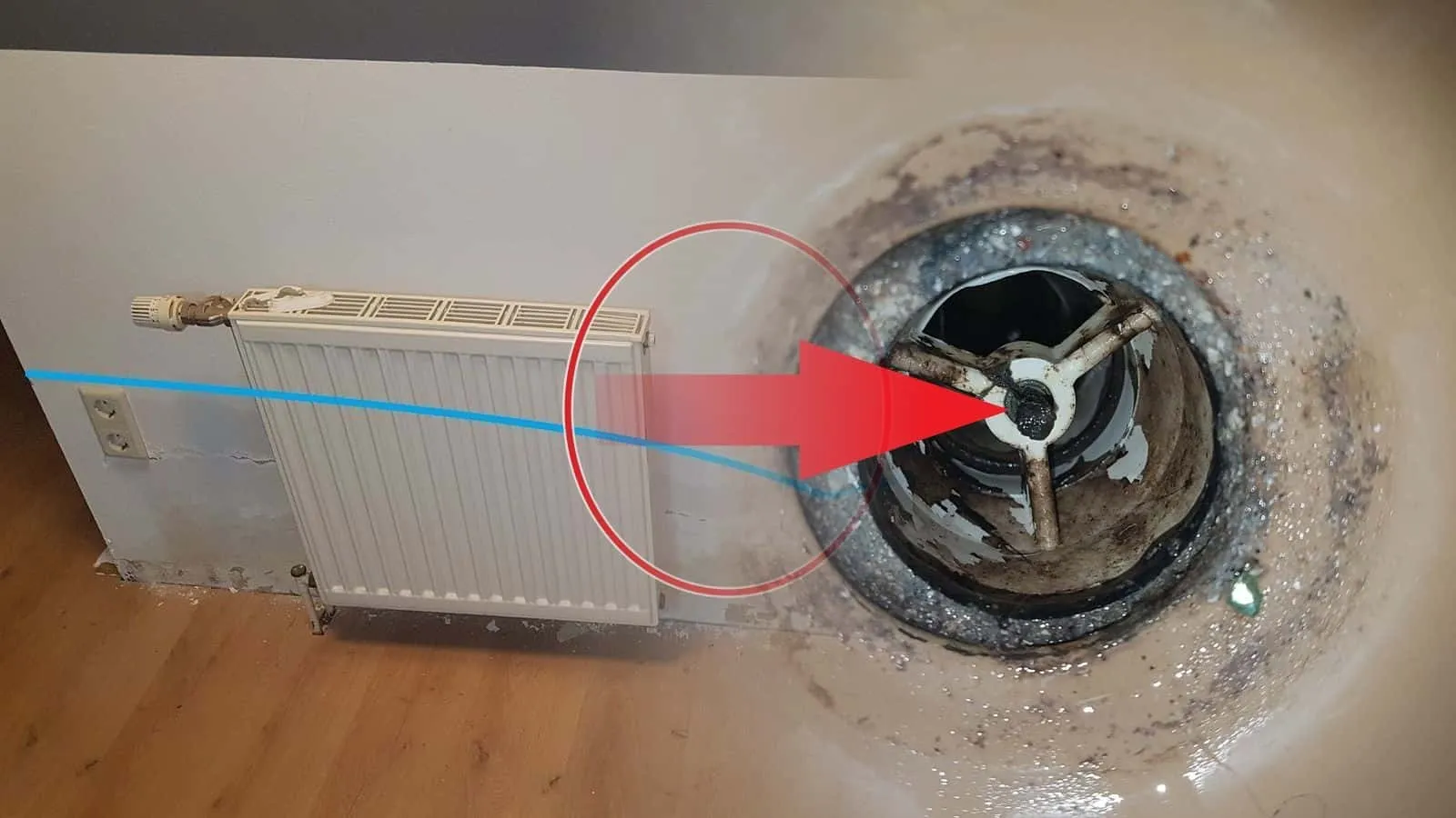 Verrosteter Ablauf mit rotem Pfeil auf das Gitter