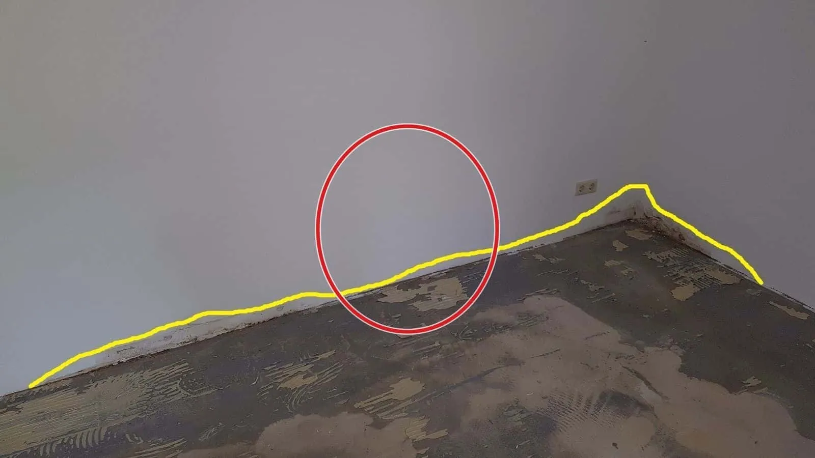 Wand über einem Boden ohne Belag, eine gelbe Linie markiert die Feuchtegrenze