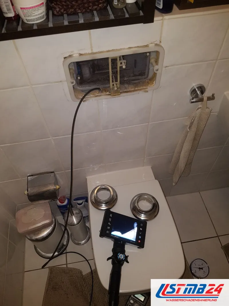 Wandhängendes WC mit abgenommener Betätigungsplatte, ein Endoskop führt in die Revisionsöffnung, der Monitor zeigt das Innere