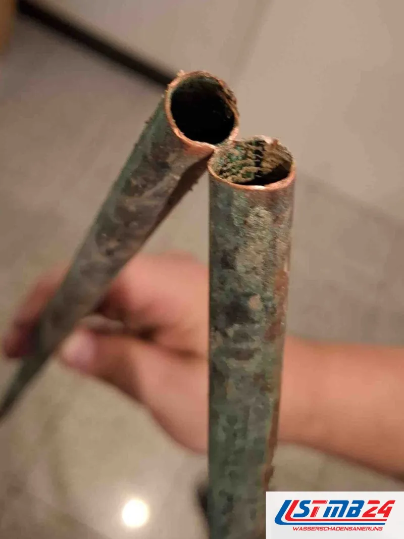 Ausgebautes Kupferrohr, an beiden Enden innen mit Kalk verkrustet und außen grün angelaufen