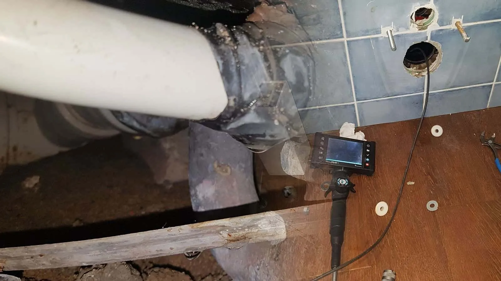 Blau gefliestes Bad mit abgebautem WC und Endoskop auf dem Boden