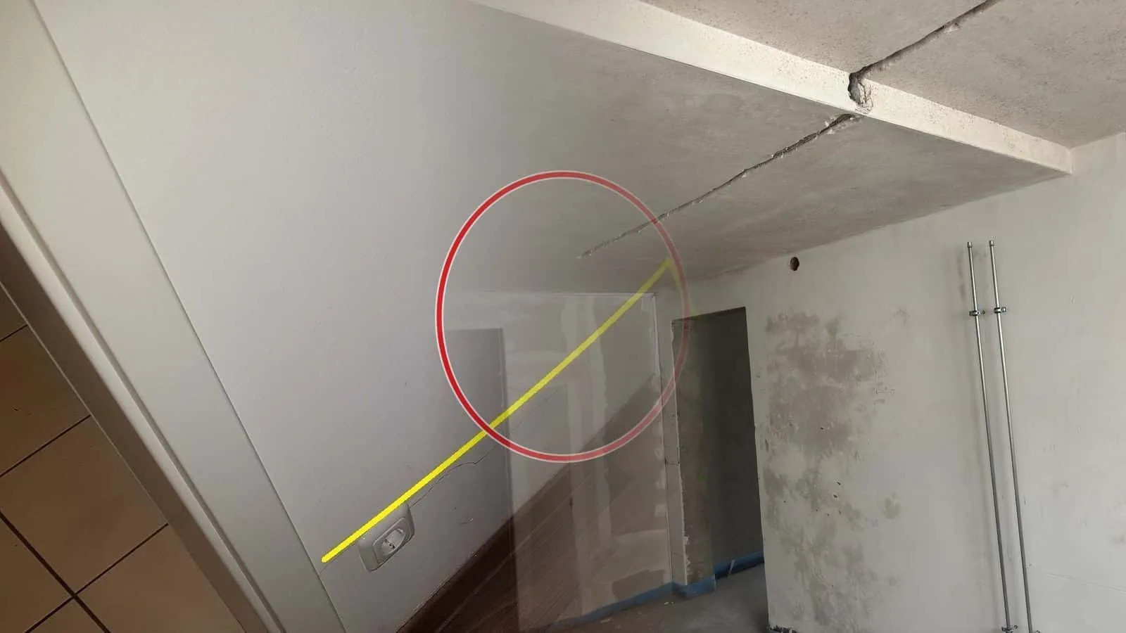 Betondecke im Rohbau mit offenen Fugen, feuchte Flecken im frischen Putz neben zwei Steigrohren